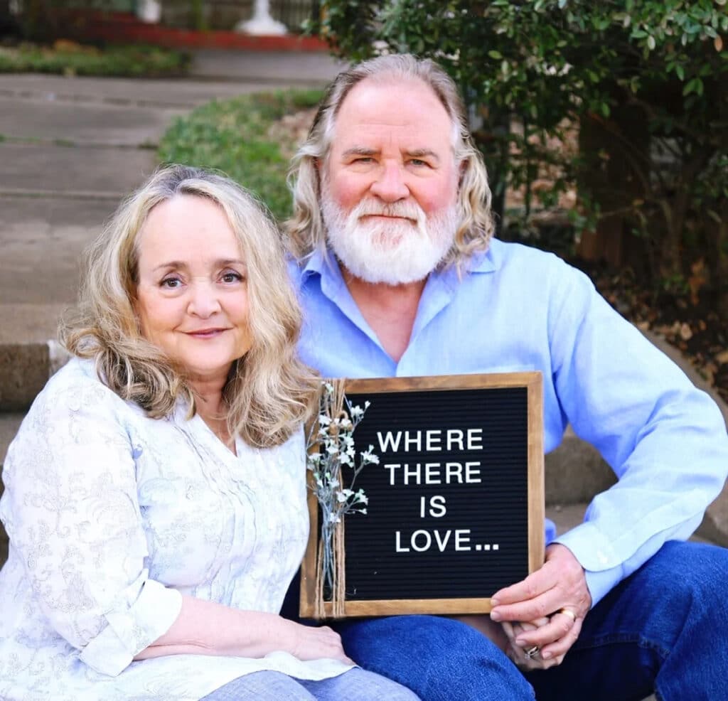 couple holding a sign that reads: where there is love...